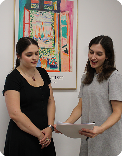 Two women standing in a gallery with a colorful painting in the background